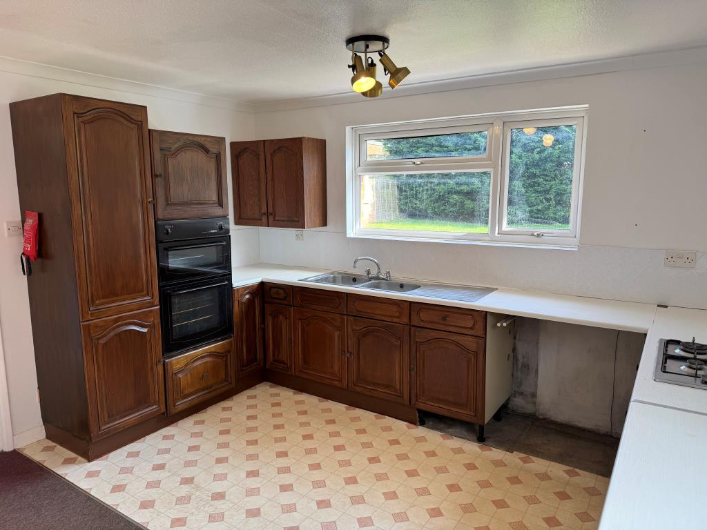 Lot: 154 - THREE-BEDROOM GROUND FLOOR APARTMENT FOR IMPROVEMENT WITH GARDENS AND GARAGE - Kitchen with units laminate flooring and view to garden